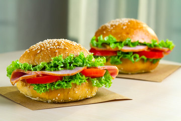 Appetizing sesame buns with fresh lettuce, tomato and ham for snack. Homemade sandwiches