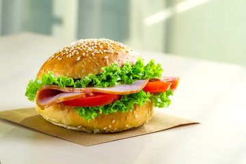 Appetizing sesame buns with fresh lettuce, tomato and ham for snack. Homemade sandwiches