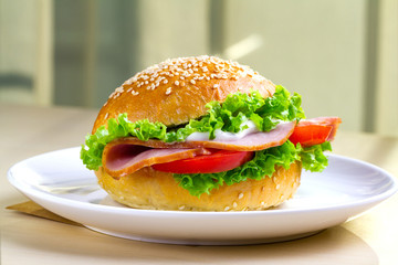 Appetizing sesame buns with fresh lettuce, tomato and ham for snack. Homemade sandwiches