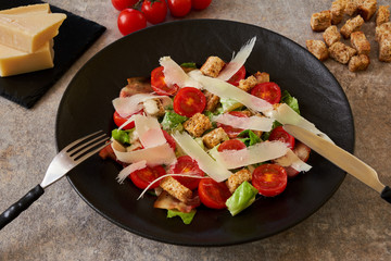 Caesar salad on a black plate, ingredients