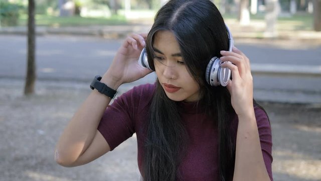 young Asian woman touching the smart watch and listening music in the park