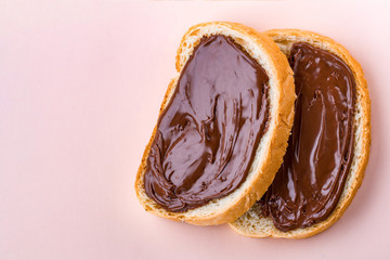 Pieces of loaf with spread chocolate paste on a pink background. Sweet, nut butter with fresh bread for breakfast. Chocolate sandwiches. Copy space