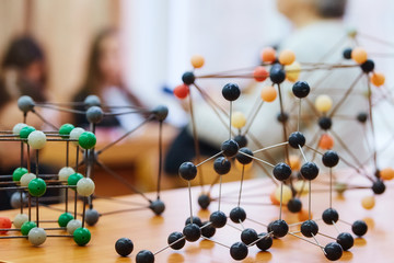 School children in a science class with a molecular model. Background image with soft focus....