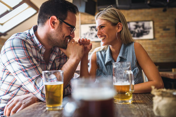 Young cheerful couple in the beer pub drinking and having good time