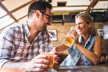 Young cheerful couple in the beer pub drinking and having good time
