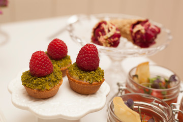Delicious tartlets filled with fruits. Dessert in glass jags. Table set.