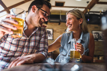 Young cheerful couple in the beer pub drinking and having good time