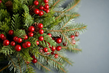 Fototapeta na wymiar Holly berries and fir branches on grey blurred background