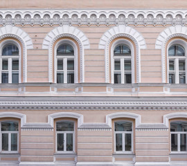 Fototapeta na wymiar Vintage architecture classical facade building. openwork architectural decorations, arched windows. Front view close up.