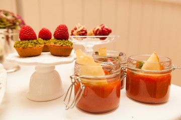 Delicious tartlets filled with fruits. Dessert in glass jags. Table set.