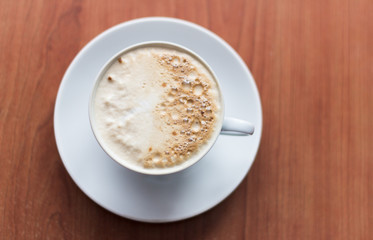 Cup of cappuccino coffee on wooden background, top view