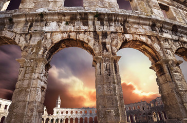 Famous Croatian city Pula old amphitheater arches with sunset sky background. Traveling in Europe...