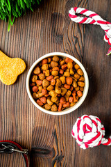 dry dog food in bowl on wooden background top view
