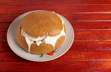 Bread with sausage, cheese and sour cream on a plate on the table.