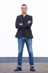 Full body confident man standing against white wall with blazer and jeans