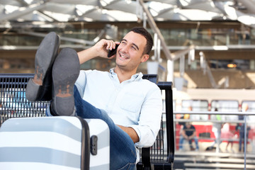 relaxed travel man talking on mobile phone at station