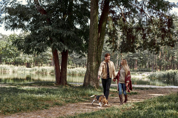 Fototapeta premium Young couple are walking with dog in forest