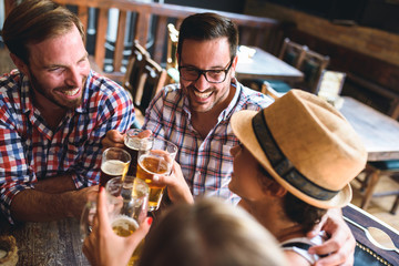 Young cheerful people in the beer pub drinking and having good time