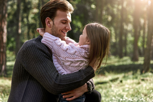 Little girl huggs her father in forest