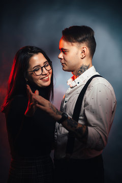 Couple in fashionable clothes on a dark smoky background