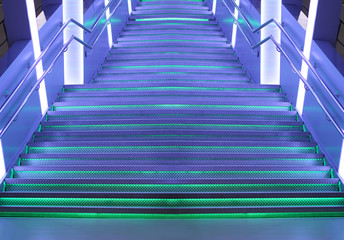 Futuristic background of LED violet green illuminated metal stairs / staircase