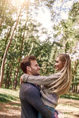 Fototapeta premium Young man holding his girlfriend on hands in autumn forest.