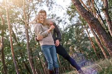 Young couple are dancing in autumn forest.