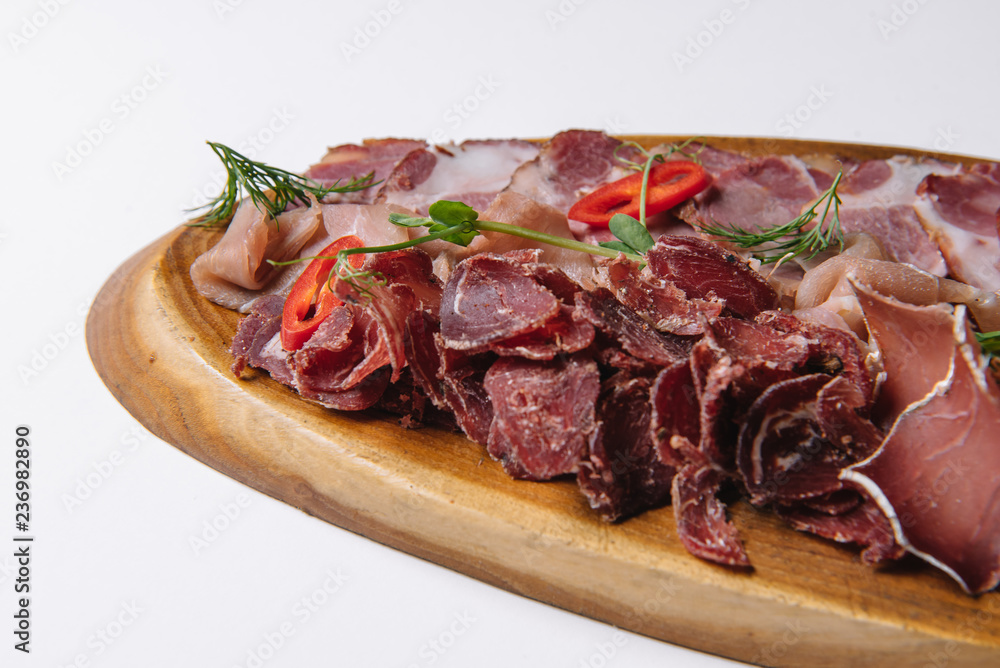 Wall mural fresh dried red beef meat fillet mignon cutted on wooden plate with many different kinds of dry spices red hot paprika crushed black pepper salt dry mustard grains over table. on a white background