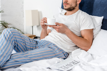 cropped image of man holding cup of coffee in morning in bedroom