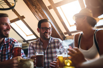 Young cheerful people in the beer pub drinking and having good time