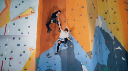 Two people are climbing an artificial training wall - Powered by Adobe