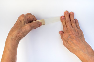 Senior woman's hands holding and using  sticky tape isolated on white background