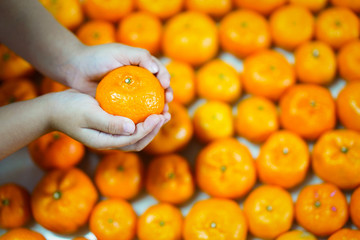 hand holding fresh orange. child girl hand with healthy fruit.         