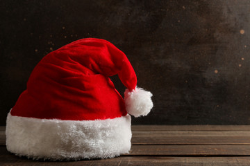 Obraz na płótnie Canvas Red Santa Claus hat standing on a dark brown background. with space for text. Christmas. new Year.