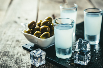 Traditional greek vodka - ouzo in shot glasses on rustic wood background