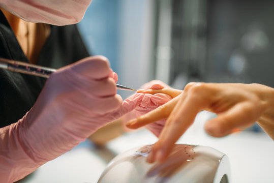 Beautician sticks the nails of female client