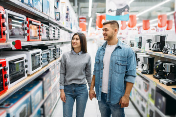 Couple looking on shelf with electric ovens