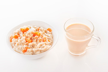 Fototapeta na wymiar Oatmeal with pumpkin and nuts in a plate and a glass of tea on a white background. Close-up. Copy space