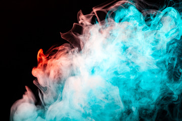 Multicolored pattern of the smoke of the green and red colors of the mystical shape on a black isolated background. Abstract pattern in the form of waves and steam.