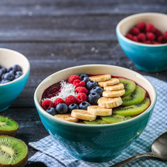 Healthy breakfast with delicious acai smoothie in bowl on dark background