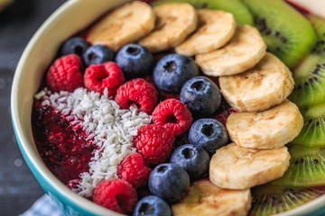 Healthy breakfast with delicious acai smoothie in bowl on dark background
