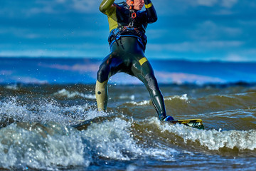 A male kiter slides on the surface of the water. Splashes of water fly apart. Close-up.