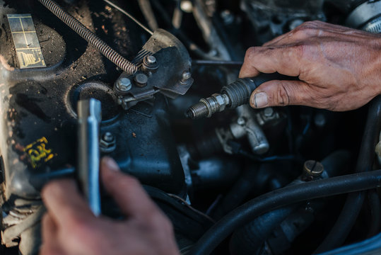 Man checks the spark plug on the old car