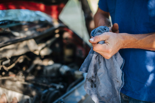 Man wipes his hands with a cloth in front of car