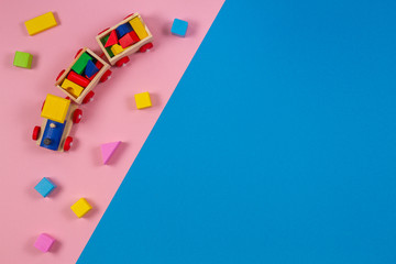 Toy background. Wooden toy train with colorful cubes on pink and blue background