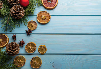 Fototapeta na wymiar Christmas baskground with handcraft dry decoration slices of orange, fir cones on a wooden blue background. Flat lay