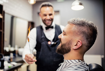 Hipster man client visiting haidresser and hairstylist in barber shop, ear hair removal.