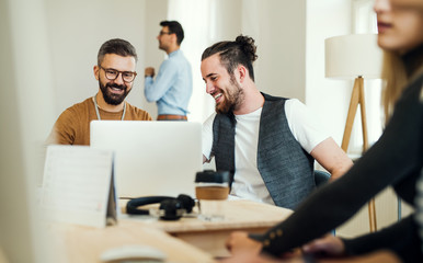 Group of young businesspeople with laptop working together in a modern office.