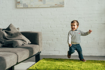 happy little boy running in living room at home