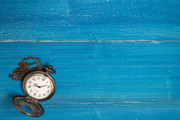 Golden vintage pocket watch put on a blue wooden table